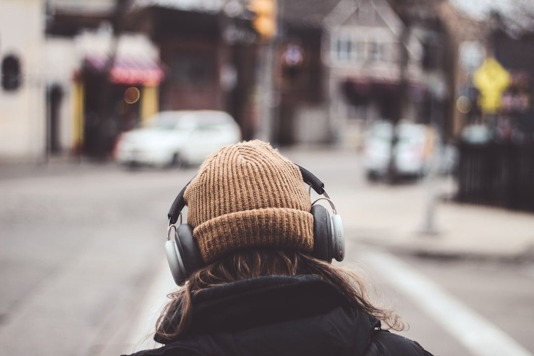 Person mit Wollmütze und Over-Ear-Kopfhörern auf einer belebten Straße